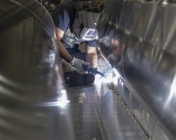 worker welding m-bracket to deck